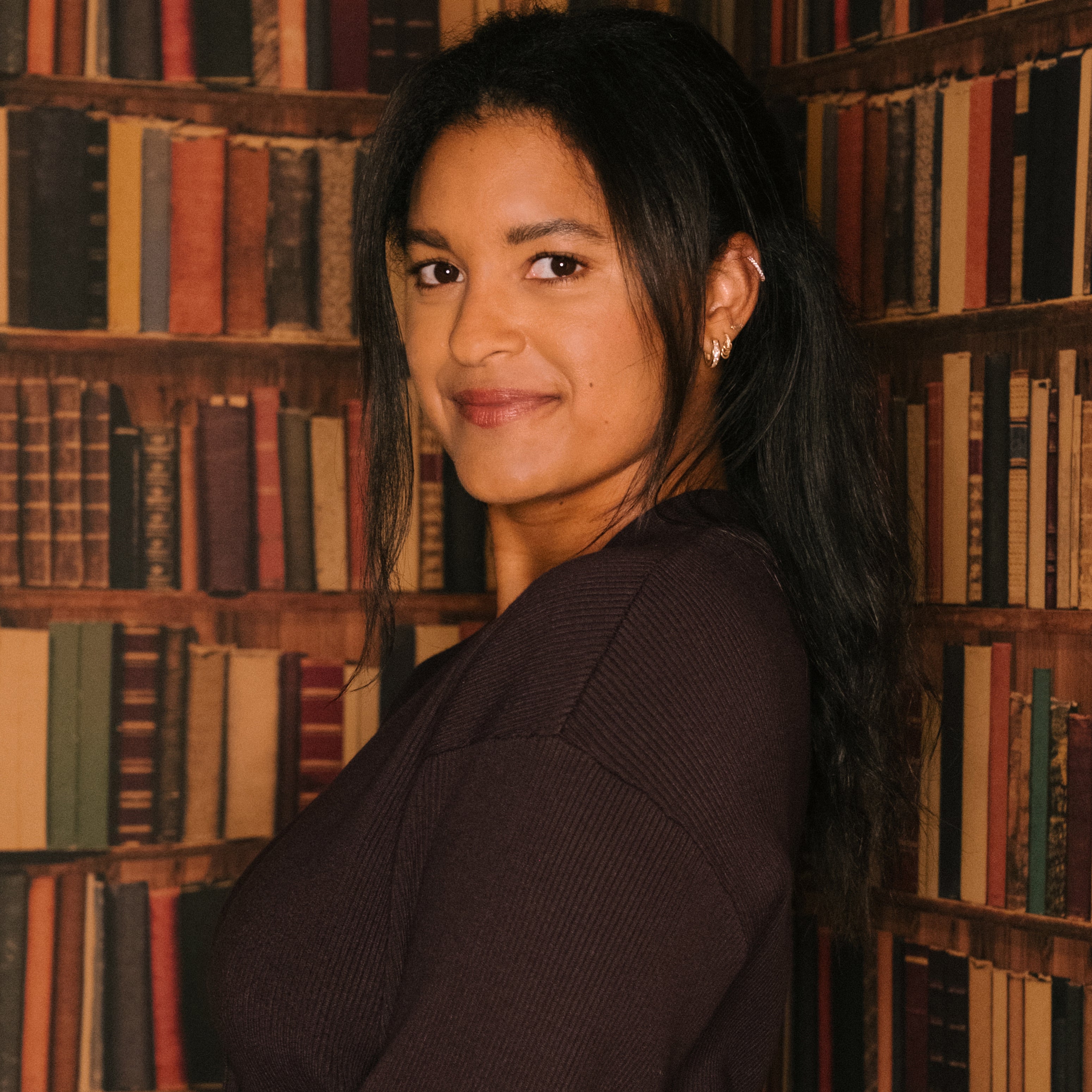 Riley Reed in front of book shelf wallpaper.